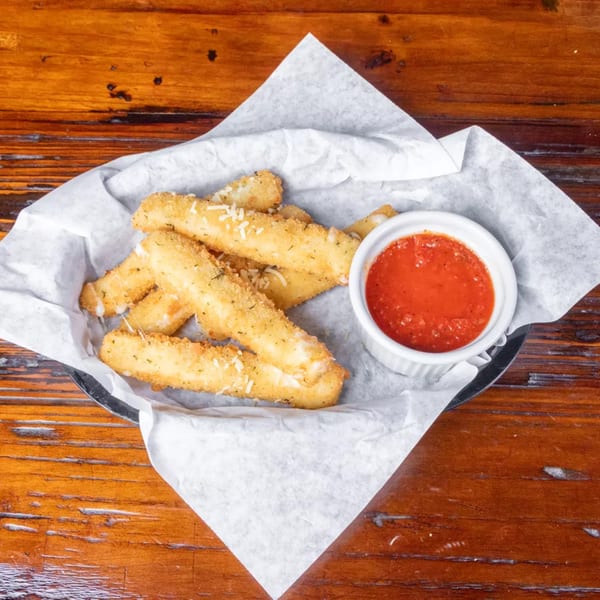 Golden-brown mozzarella sticks with parmesan cheese and a side of marinara sauce on a wooden table.